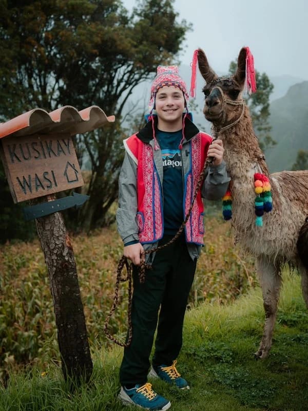 Joven viajero compartiendo una experiencia con una llama en los Andes
